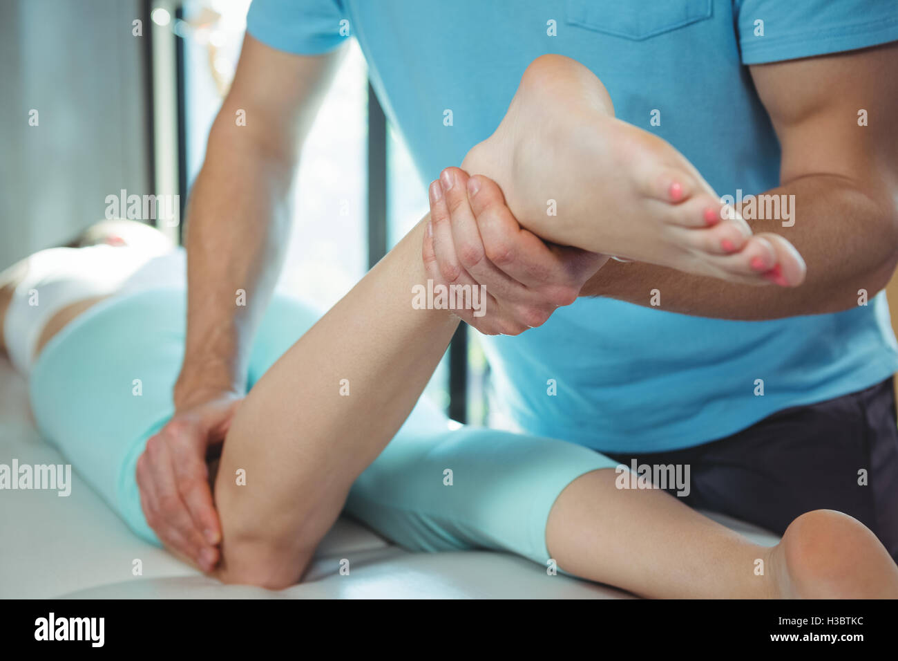 Fisioterapista dando la terapia fisica per la gamba di un paziente di sesso femminile Foto Stock