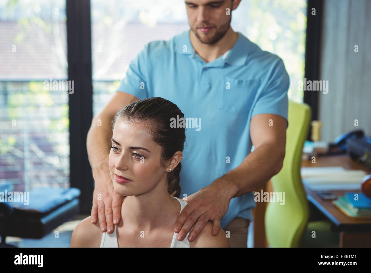 Fisioterapista massaggiare la spalla di un paziente di sesso femminile Foto Stock