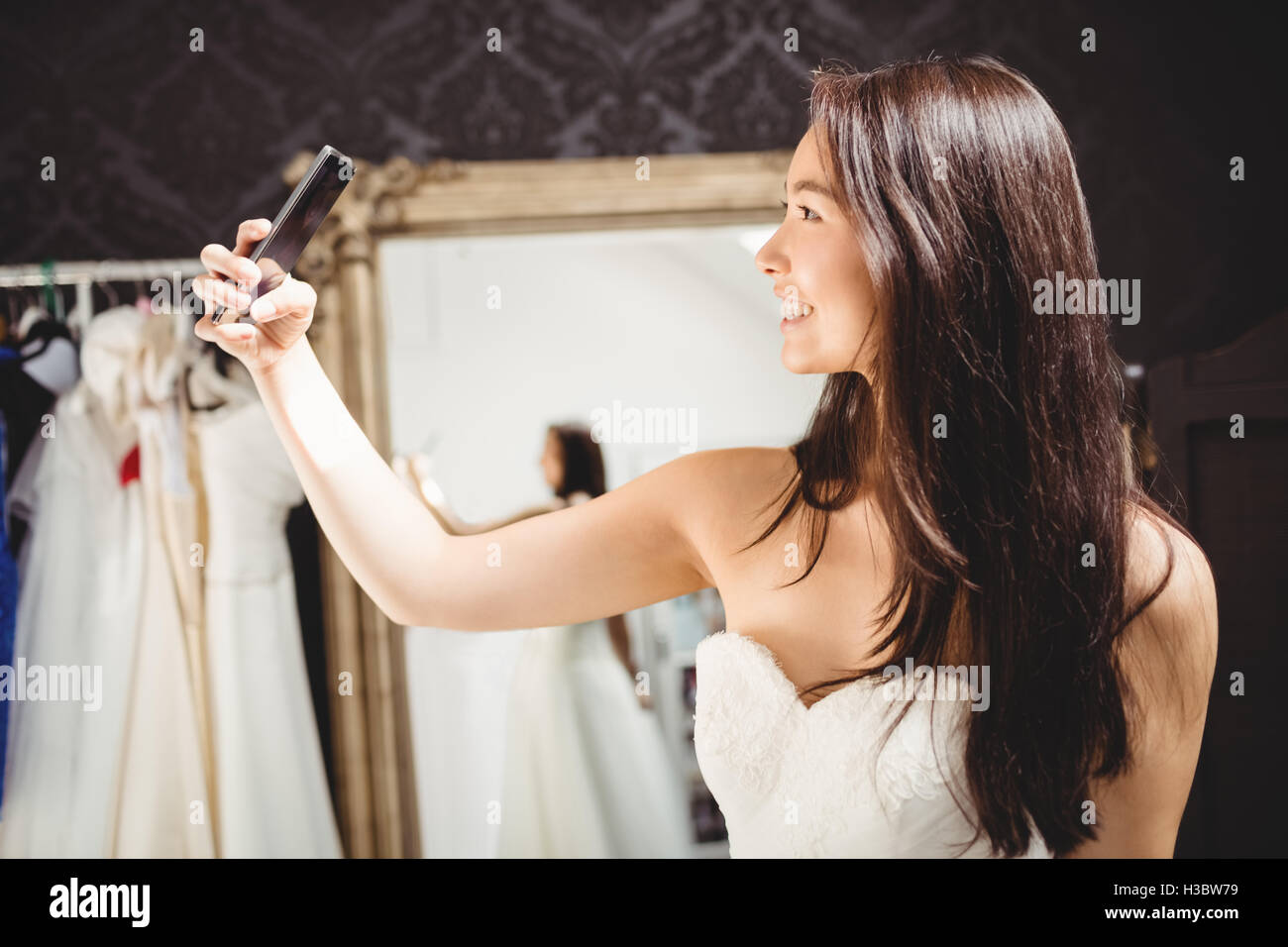 Donna prendendo selfie durante il tentativo su di un abito da sposa Foto Stock