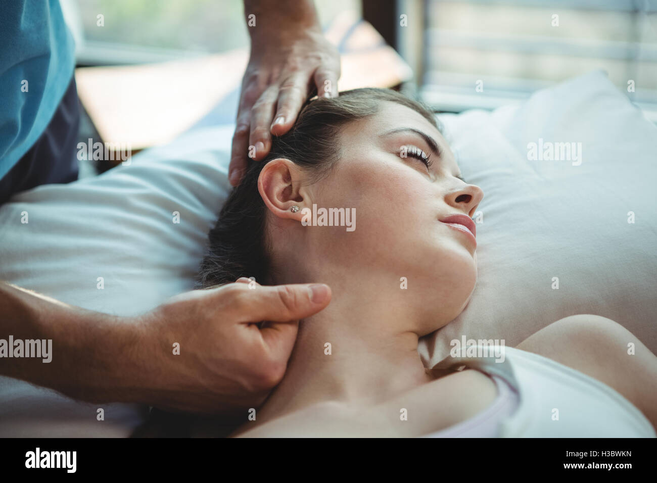 Fisioterapista maschio dando massaggio al collo al paziente di sesso femminile Foto Stock