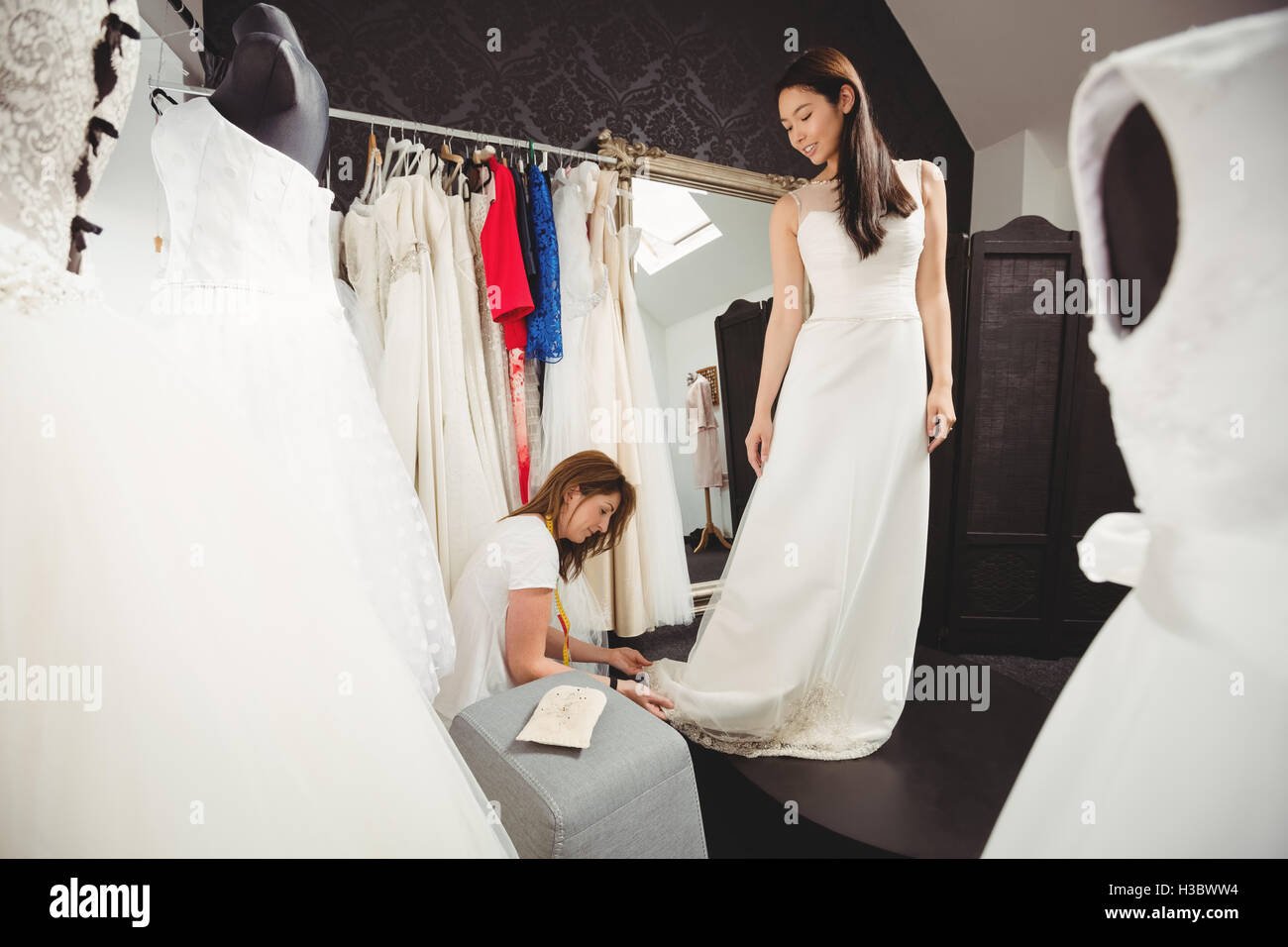 Donna cercando in abito da sposa con il contributo di designer creativo Foto Stock