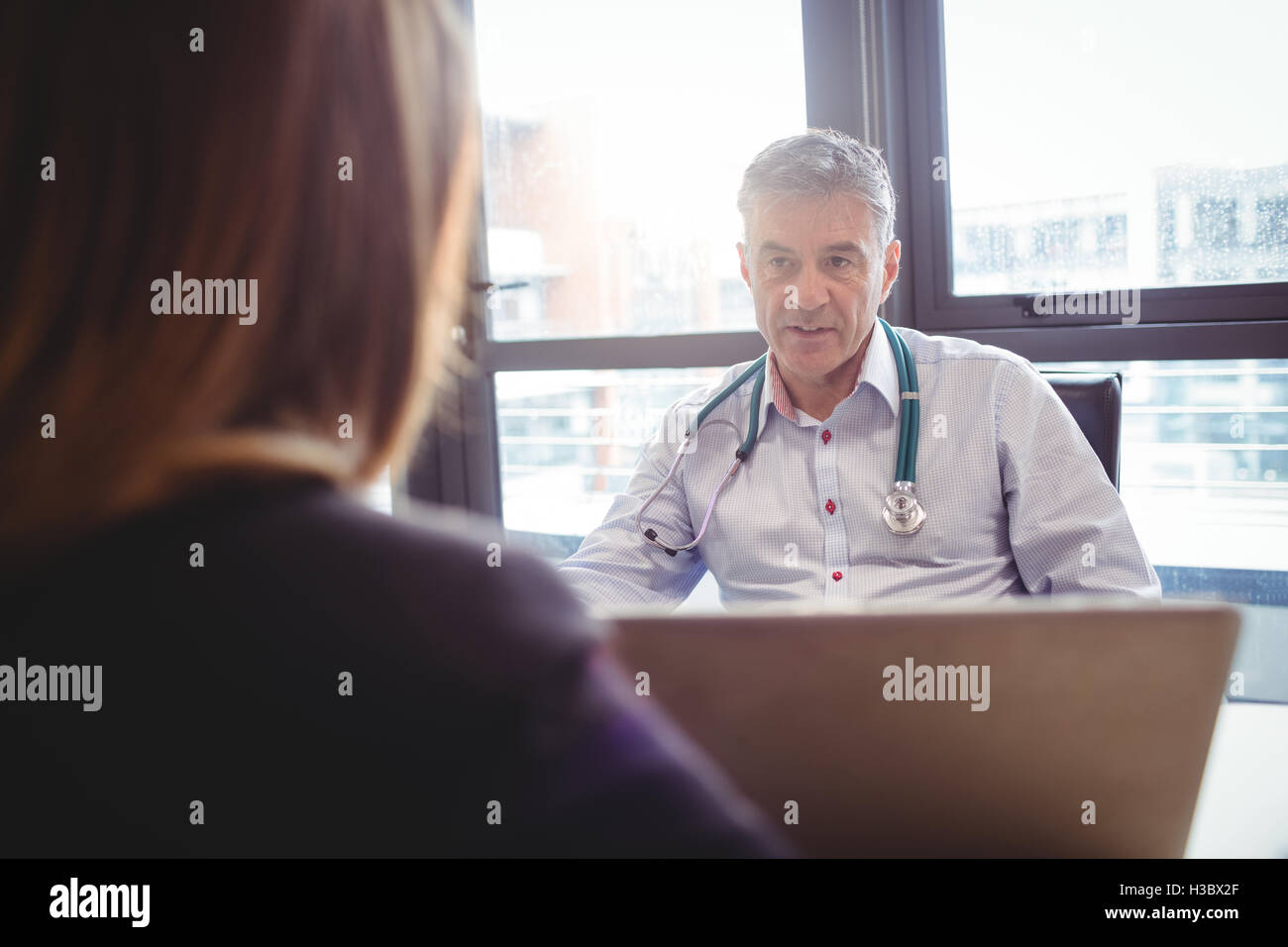 Medico seduto alla sua scrivania di parlare al paziente Foto Stock