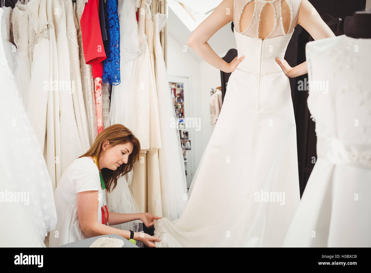 Donna cercando in abito da sposa con il contributo di designer creativo Foto Stock