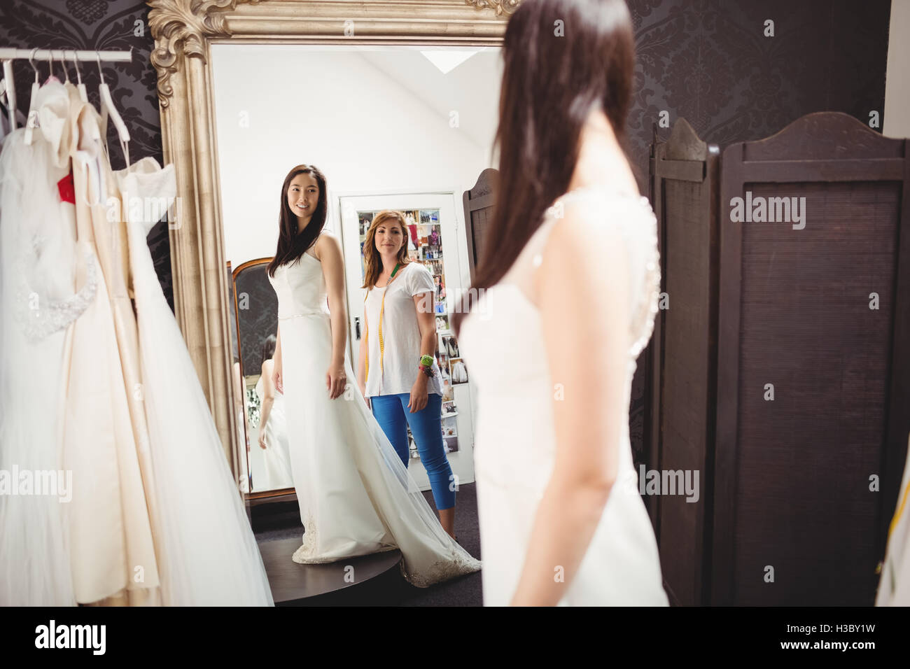 Donna cercando in abito da sposa con il contributo di designer creativo Foto Stock