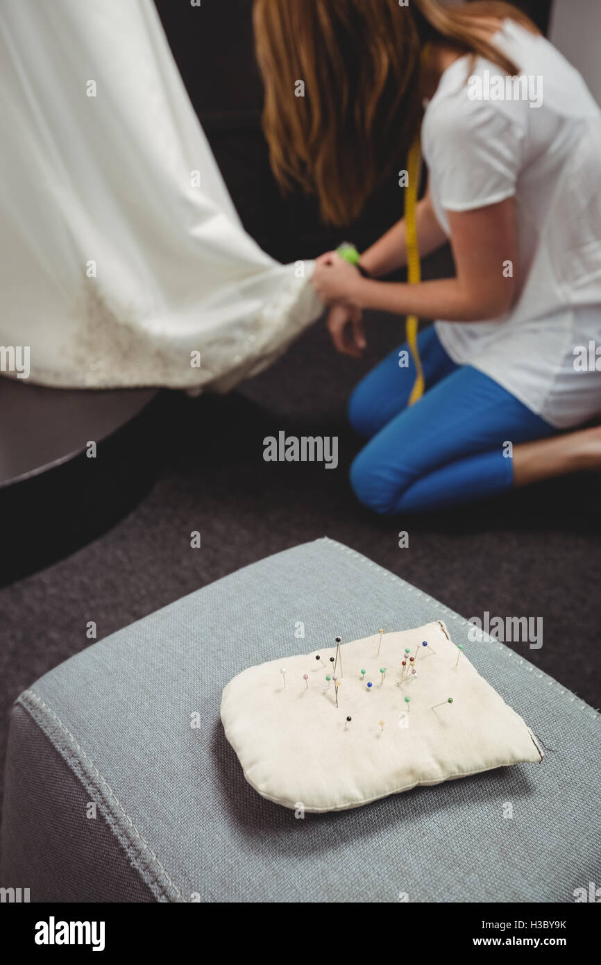 Puntaspilli sul divano e creative designer che lavora in background Foto Stock