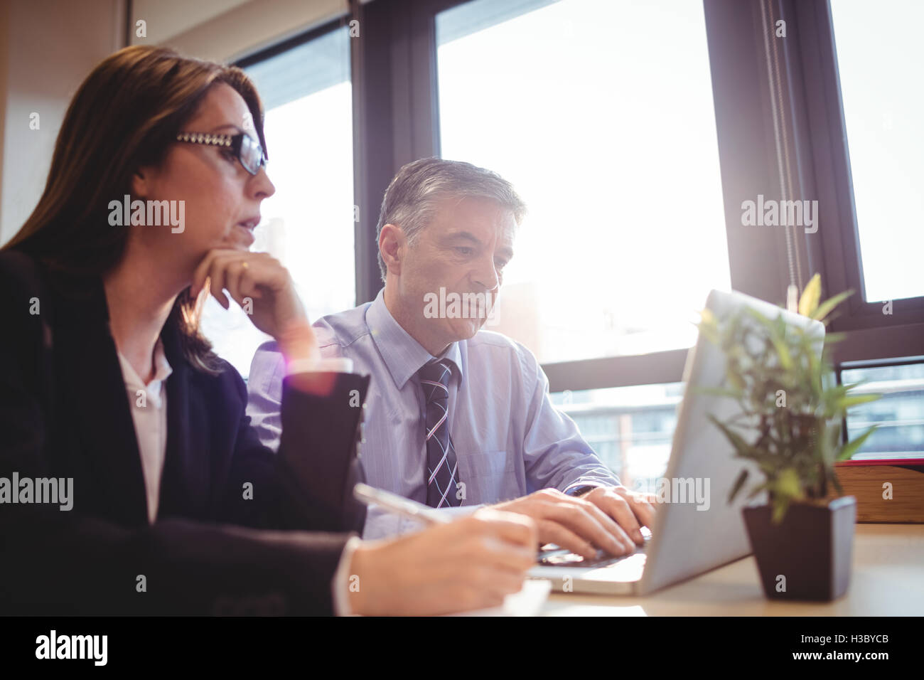 Imprenditore discutendo con un collega su laptop Foto Stock