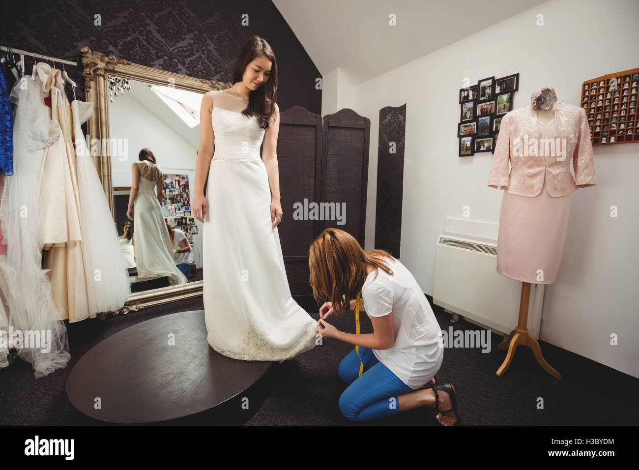 Donna cercando in abito da sposa con il contributo di designer creativo Foto Stock