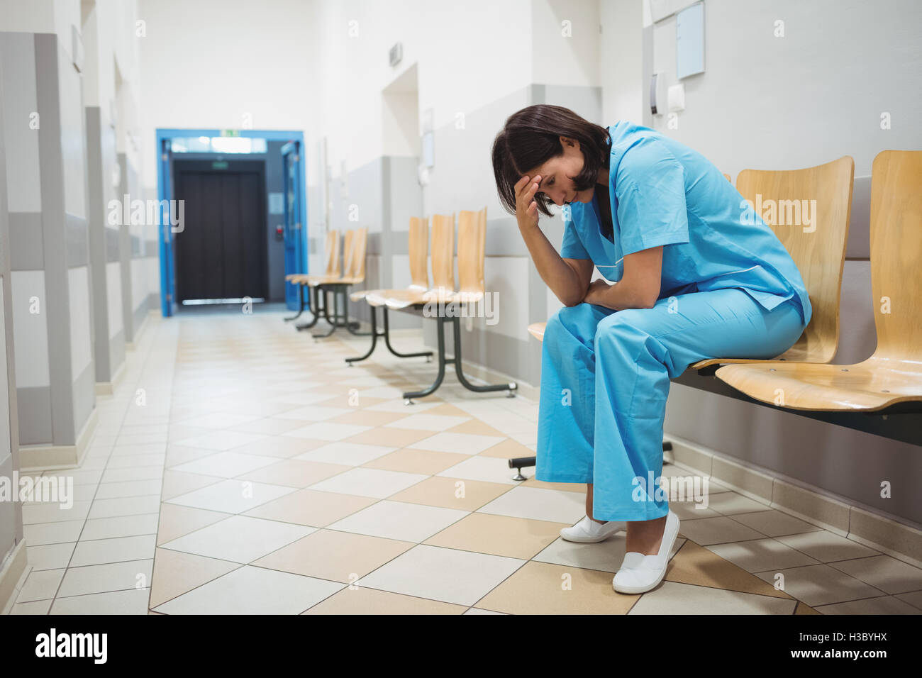 Triste infermiere seduto sulla sedia Foto Stock