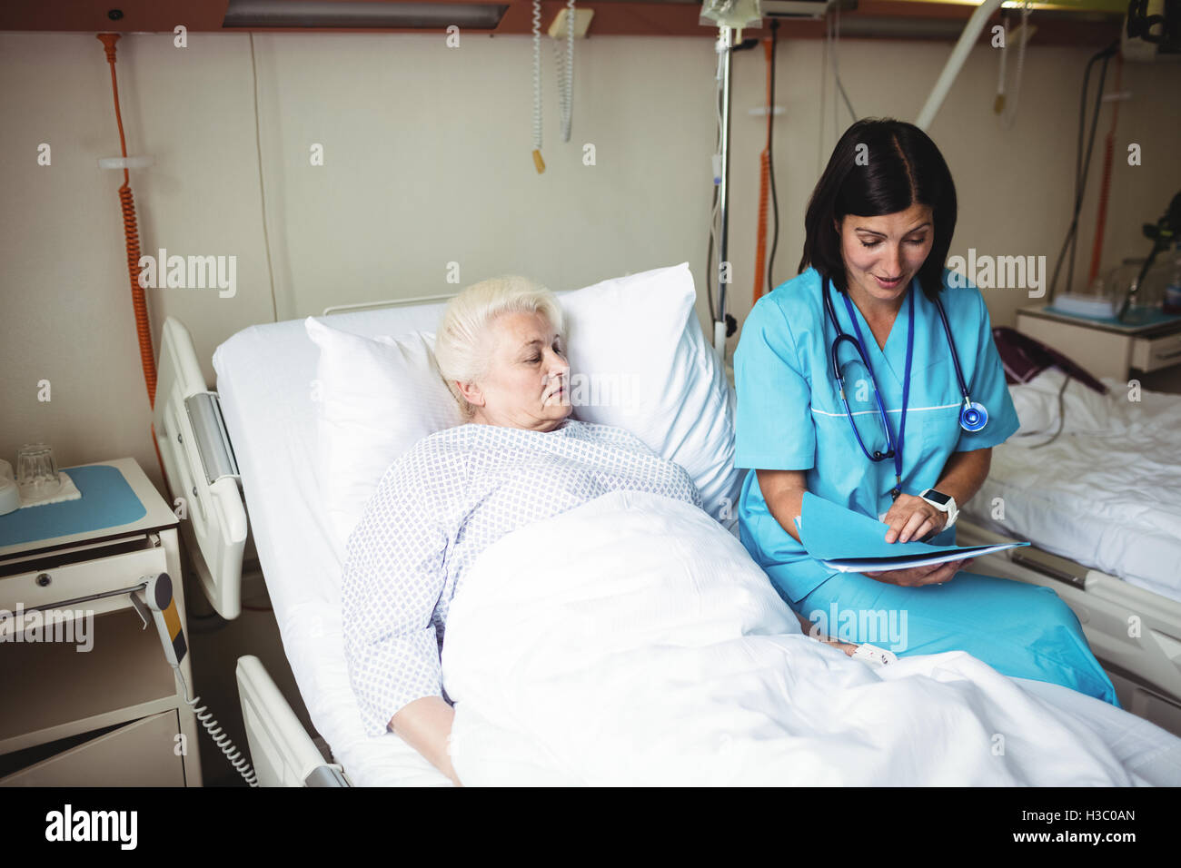 L'infermiera interagenti con il senior paziente mentre guardando al report Foto Stock