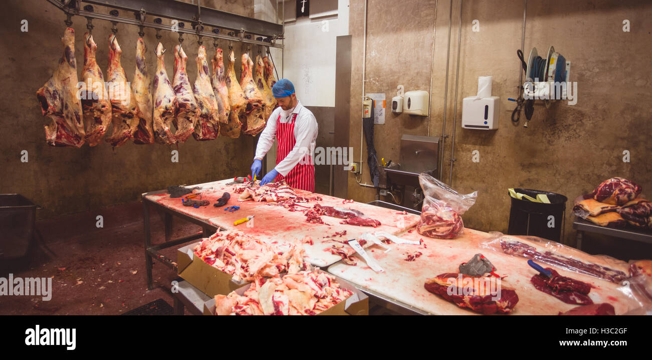 Macellaio di tritare la carne nella stanza di deposito Foto Stock