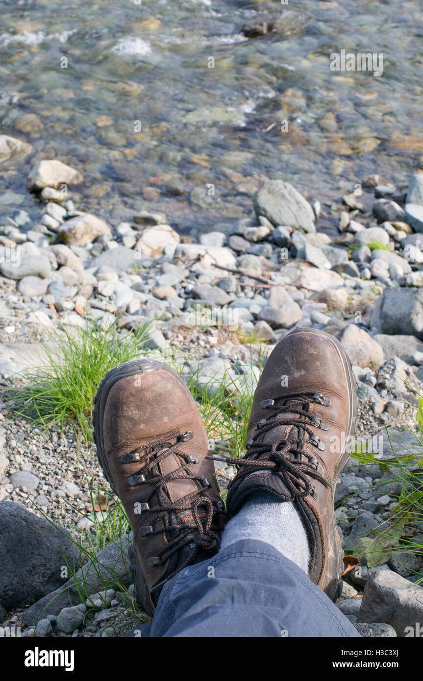 Piedi e stivali di walker in appoggio vicino torrente nel Lake District Inghilterra, Regno Unito Foto Stock