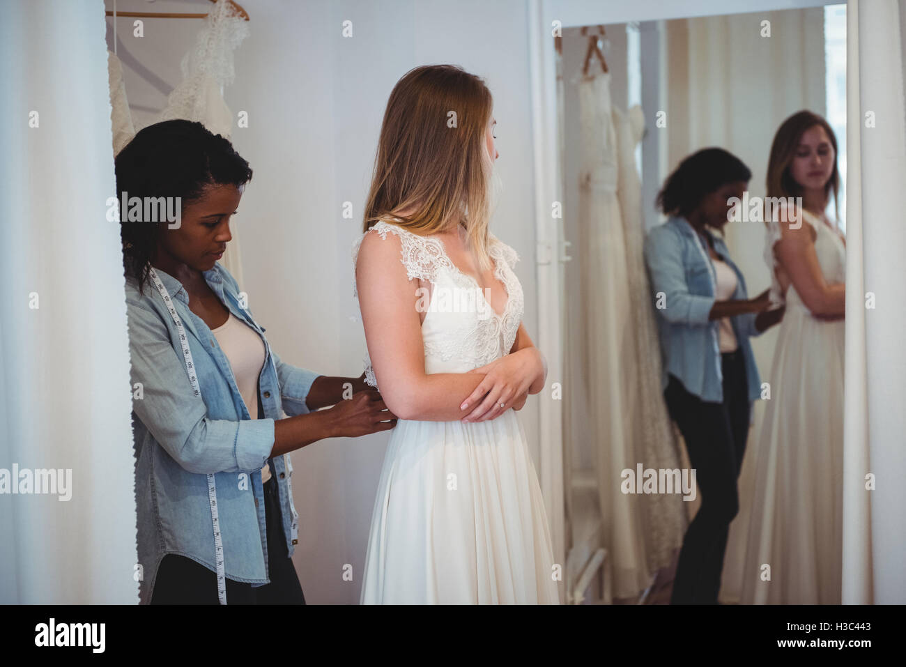 Donna cercando in abito da sposa con il contributo di designer di moda Foto Stock