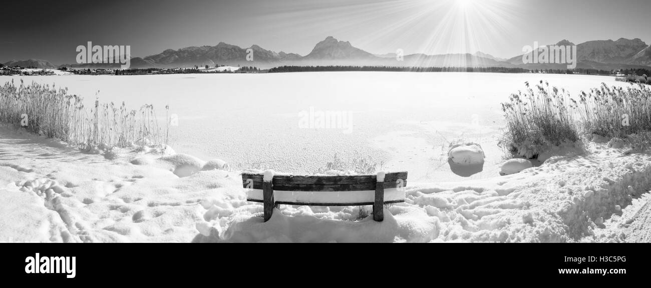 Ampio panorama del paesaggio in Baviera con montagne delle Alpi e del lago in inverno con neve fresca sulla panca in legno Foto Stock