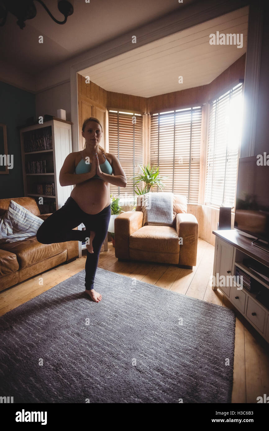 Donna incinta di eseguire lo yoga in salotto Foto Stock