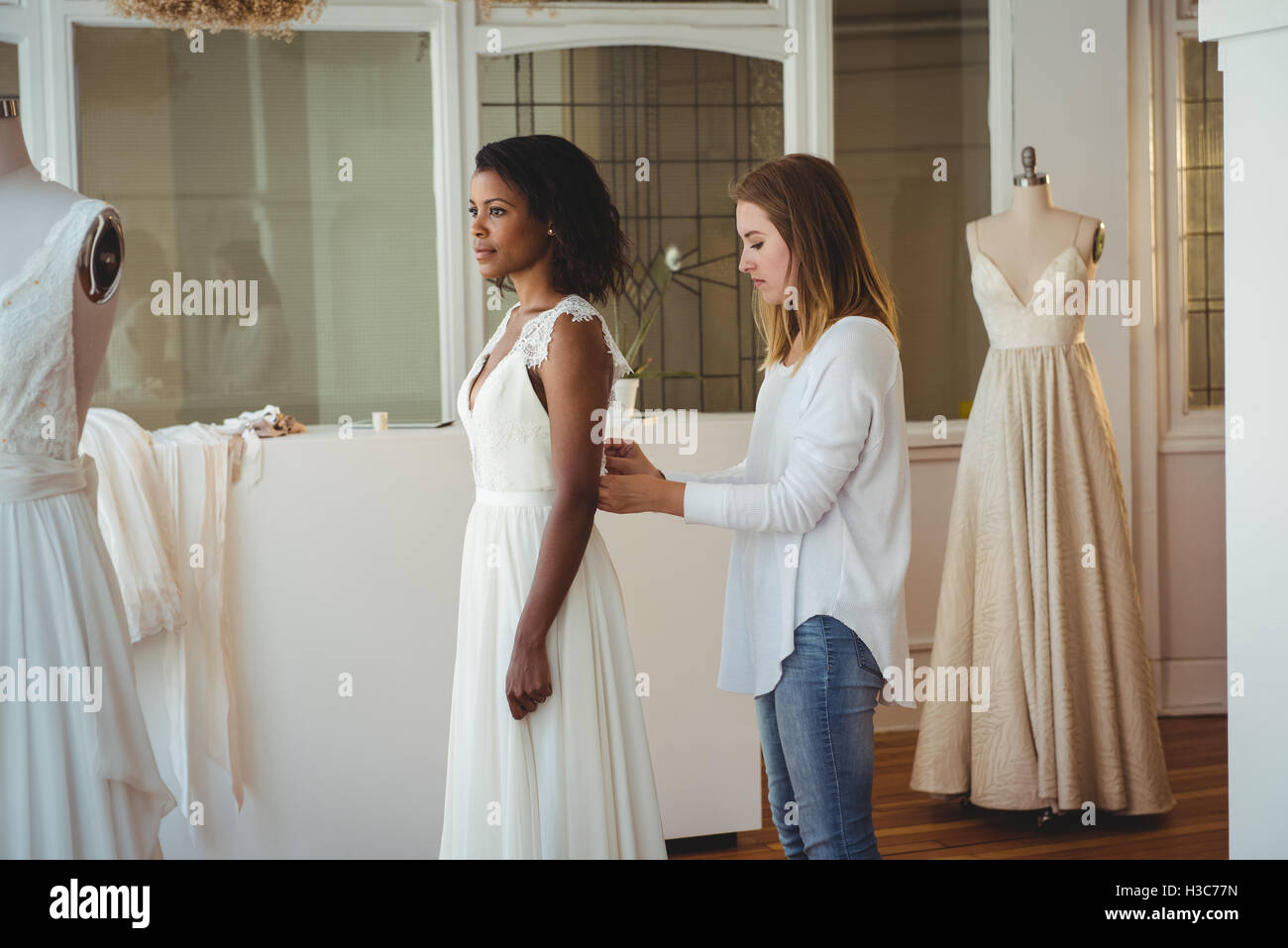 Donna cercando in abito da sposa con il contributo di designer di moda Foto Stock