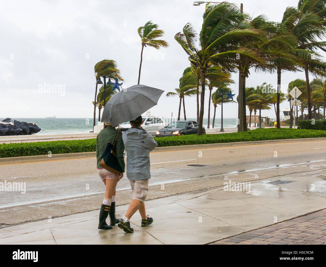 Persone che camminano con ombrello sotto la pioggia torrenziale durante la tempesta tropicale sul lungomare di Fort Lauderdale, Florida, Stati Uniti d'America Foto Stock