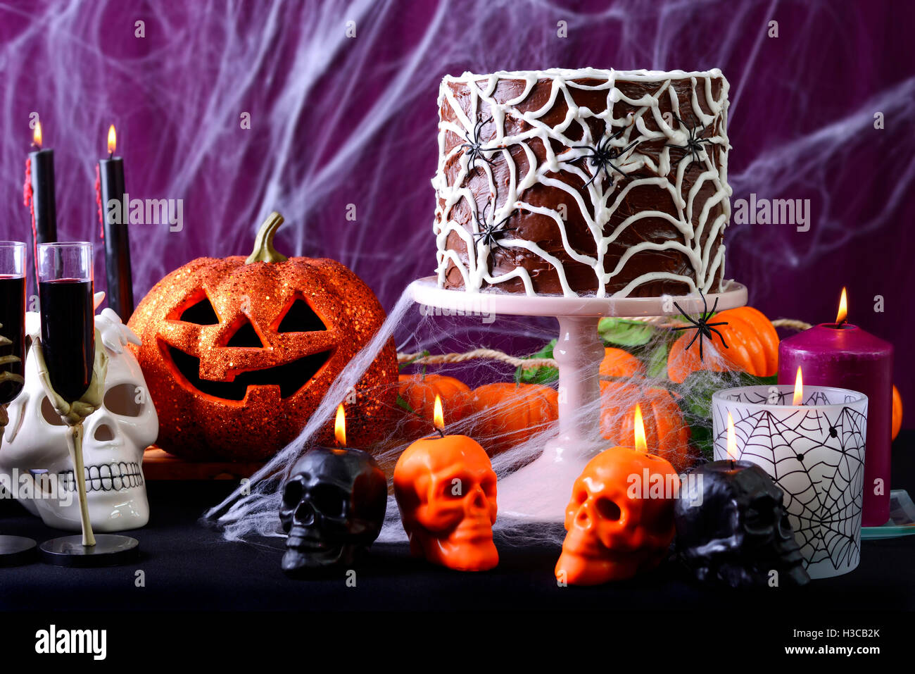 Happy Halloween Party Tabella con cioccolato spider web torta e candele accese contro viola spider web sfondo. Foto Stock