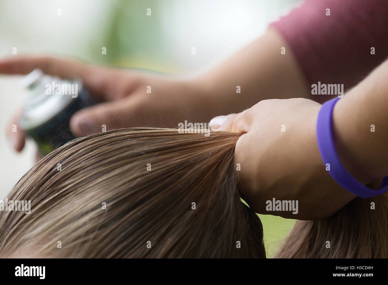 Spruzzare i capelli con la lacca e dropplets visibile sulla fibra del pelo, hair styling prima competizione sportiva. Foto Stock