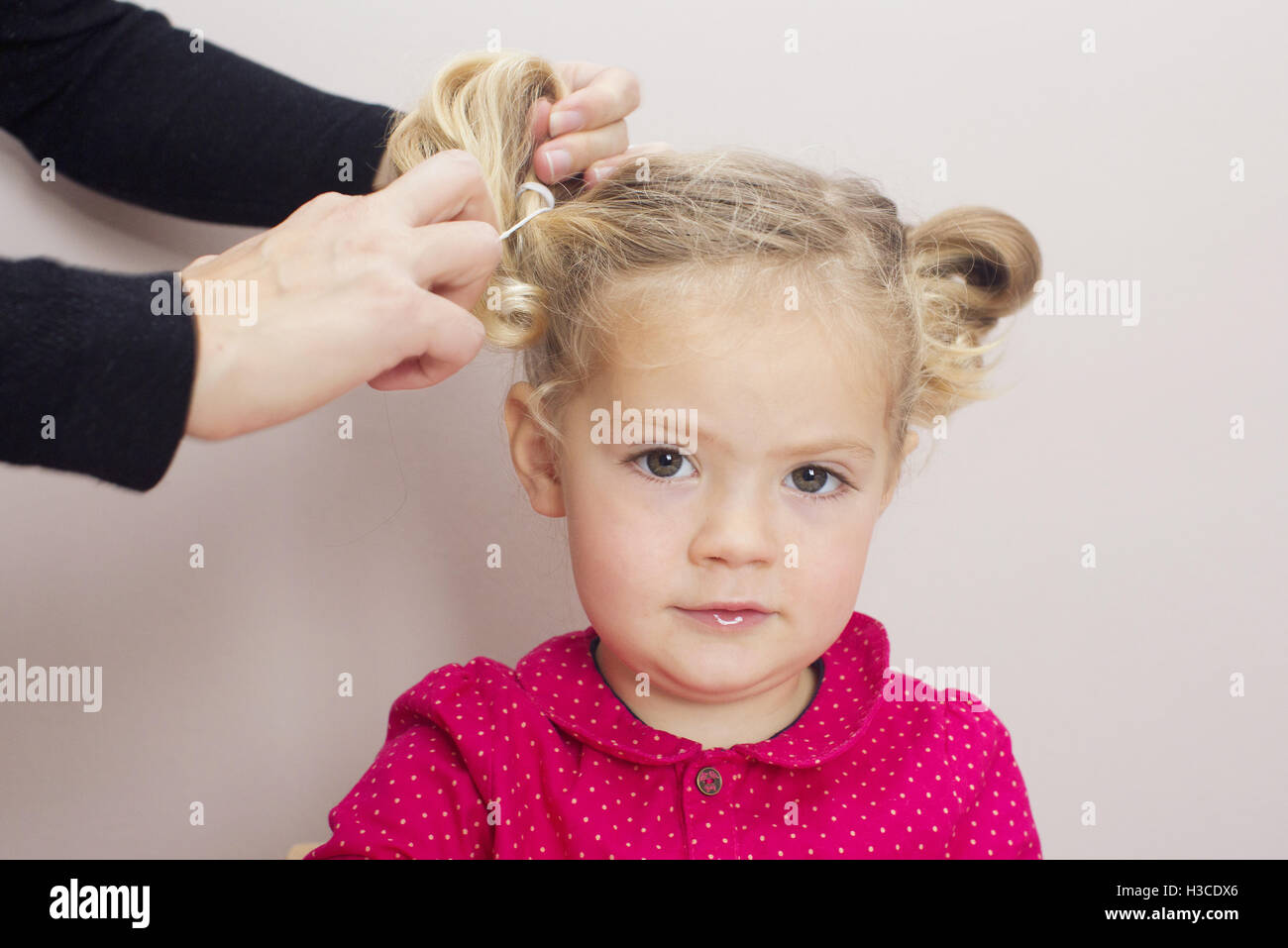 Bambina avente i suoi capelli disposti in pigtail Foto Stock