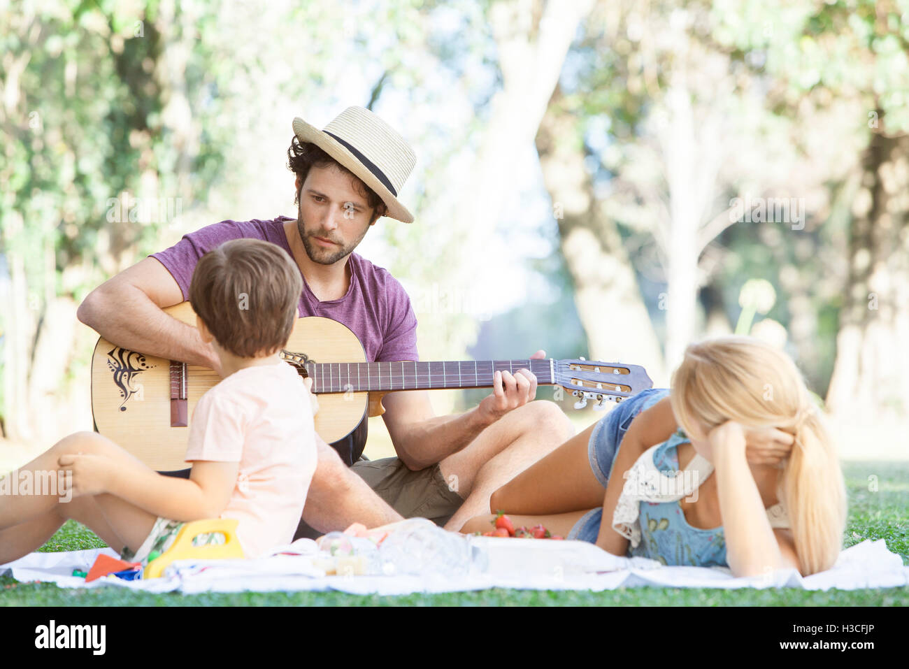 L'uomo suonare la chitarra acustica per moglie e figlio Foto Stock