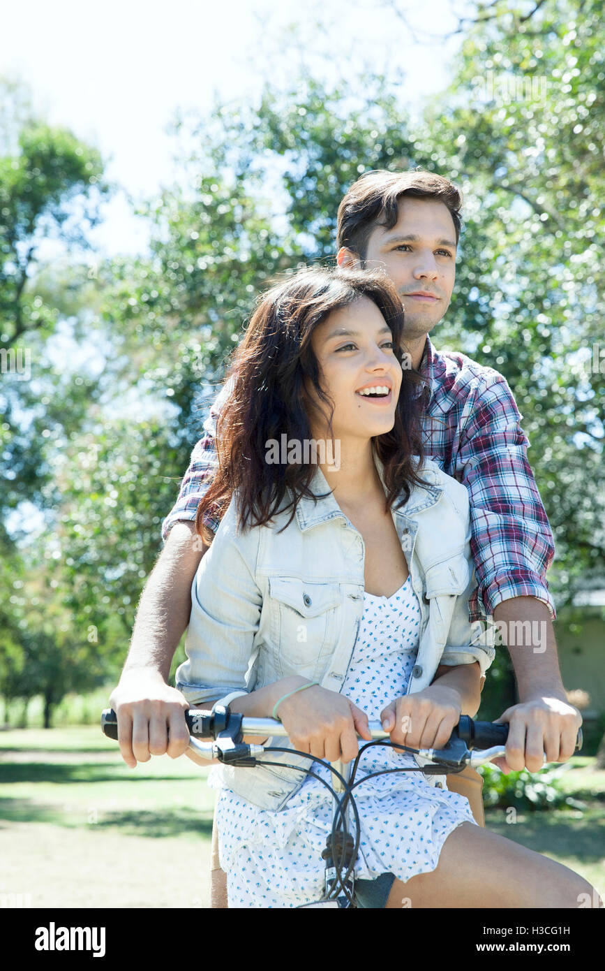 Coppia giovane equitazione Bicicletta insieme con la fidanzata sidesaddle seduti sulla traversa Foto Stock