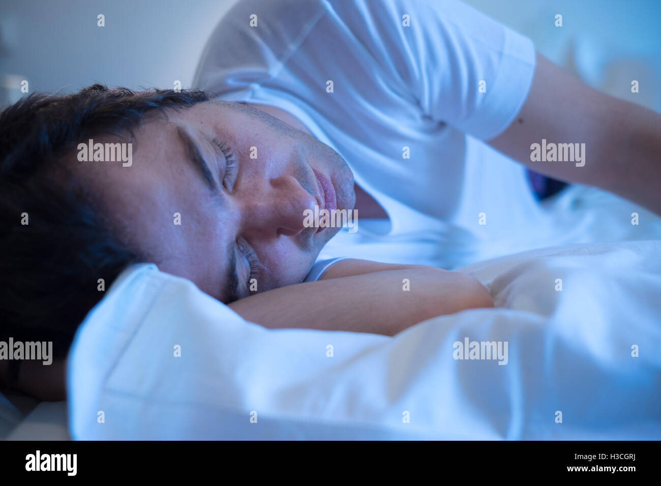Uomo disteso nel letto e dormire di notte Foto Stock