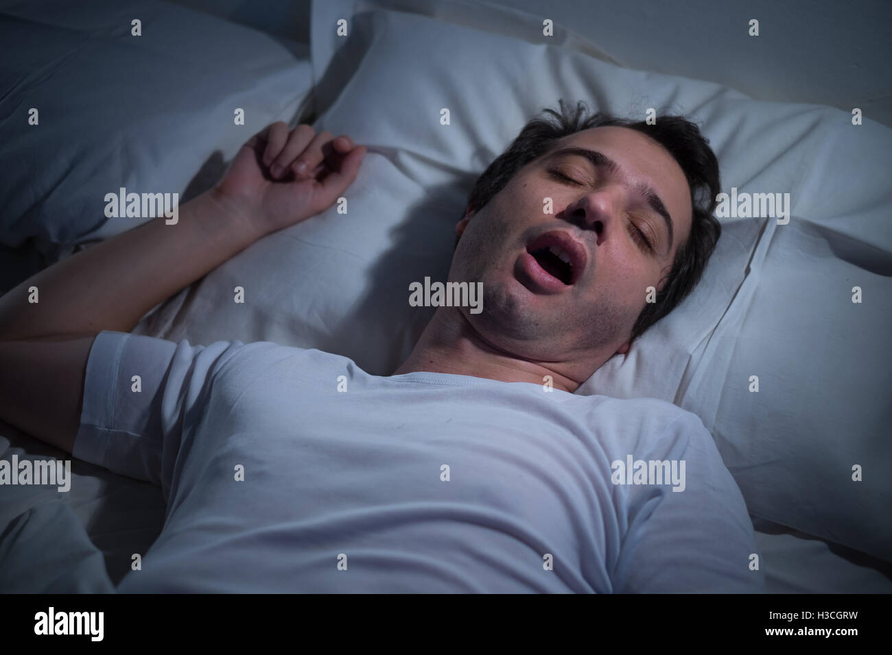 L uomo è dormire nel suo letto di notte Foto Stock