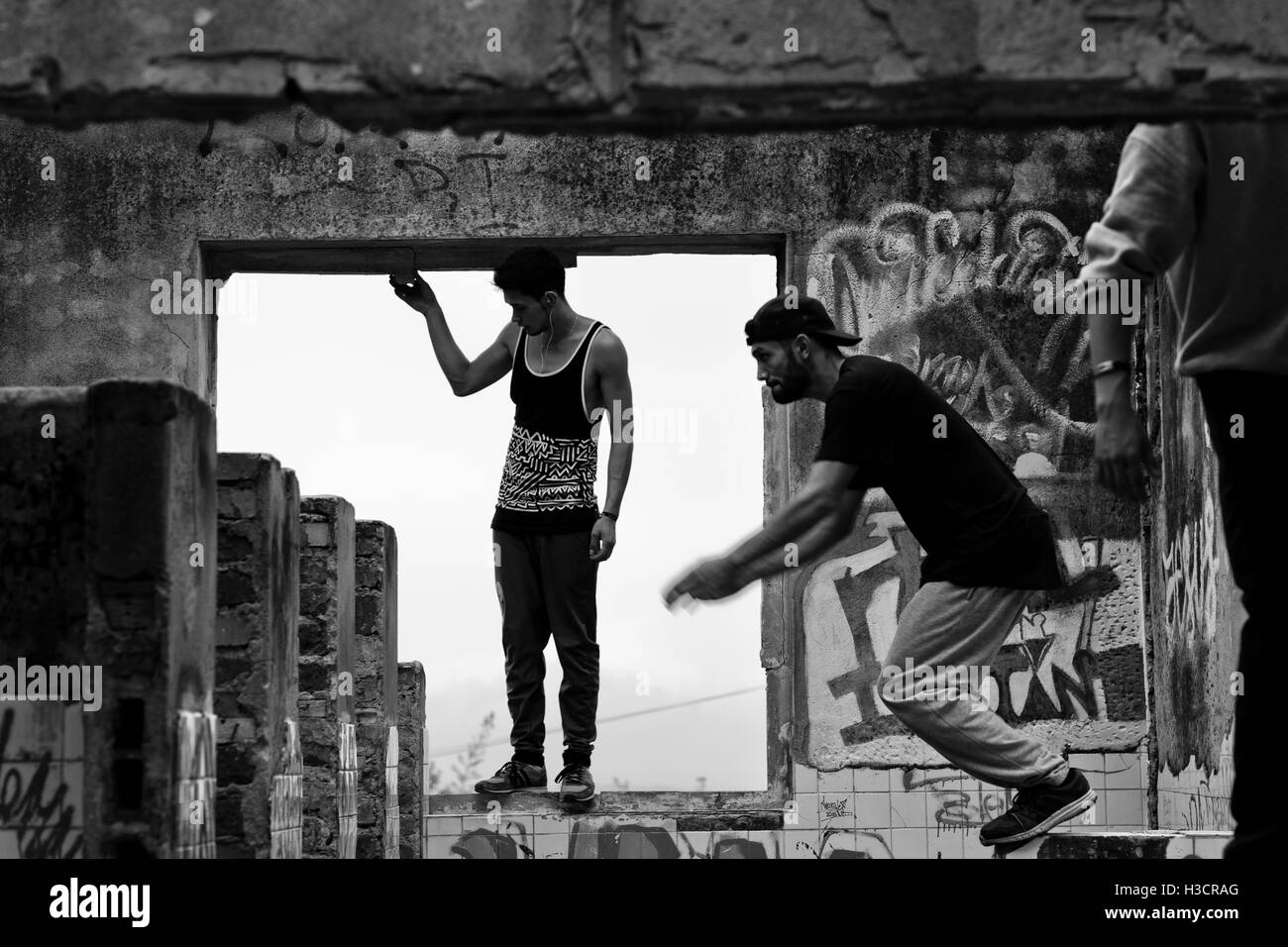 Colombiano atleti parkour saltare all'interno di una casa in rovina durante una corsa libera formazione dei Plus team parkour in Bogotá, Colombia. Foto Stock