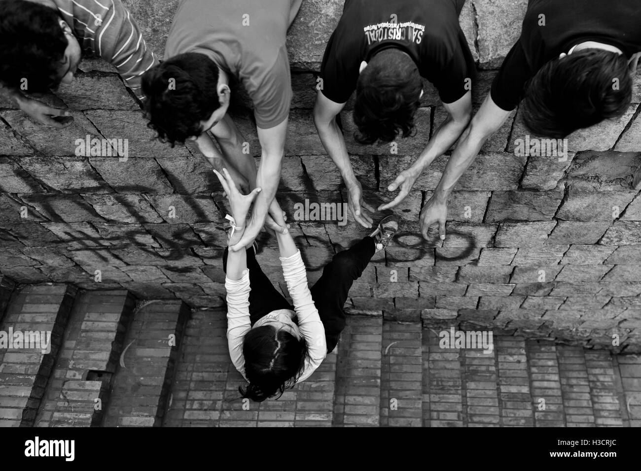Un colombiano freerunner femmina, appeso su i suoi compagni' le mani, si arrampica sulla parete durante un allenamento parkour in Bogotá, Colombia. Foto Stock