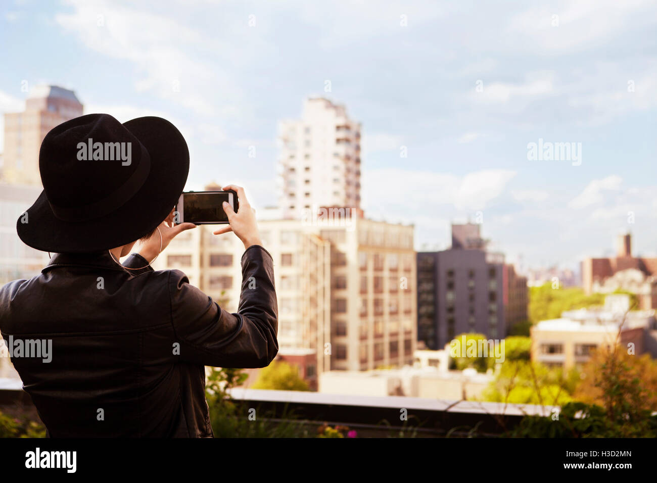 Vista posteriore della donna fotografare edifici attraverso smart phone dalla terrazza Foto Stock