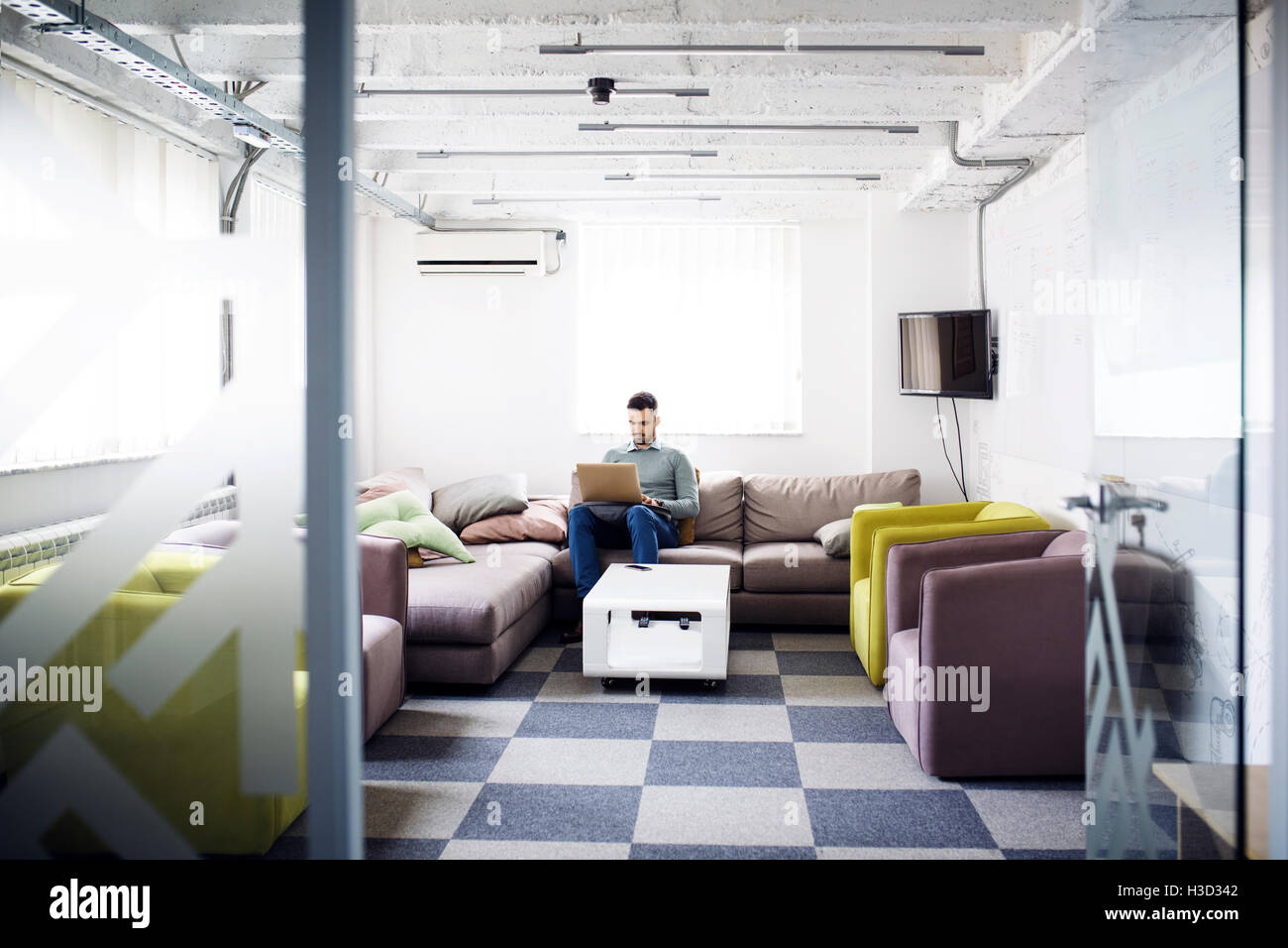 uomo d'affari che utilizza un computer portatile seduto sul divano nella hall dell'ufficio Foto Stock