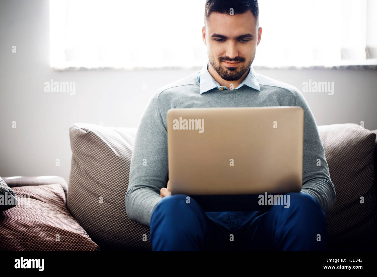 uomo d'affari che utilizza un computer portatile sul divano nella hall dell'ufficio Foto Stock