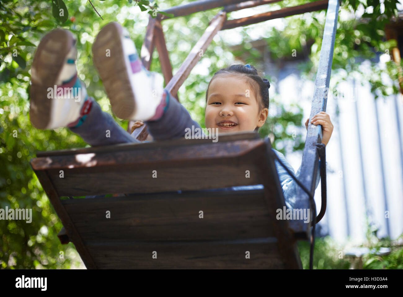 Ritratto di felice ragazza che gioca su swing sul cortile Foto Stock