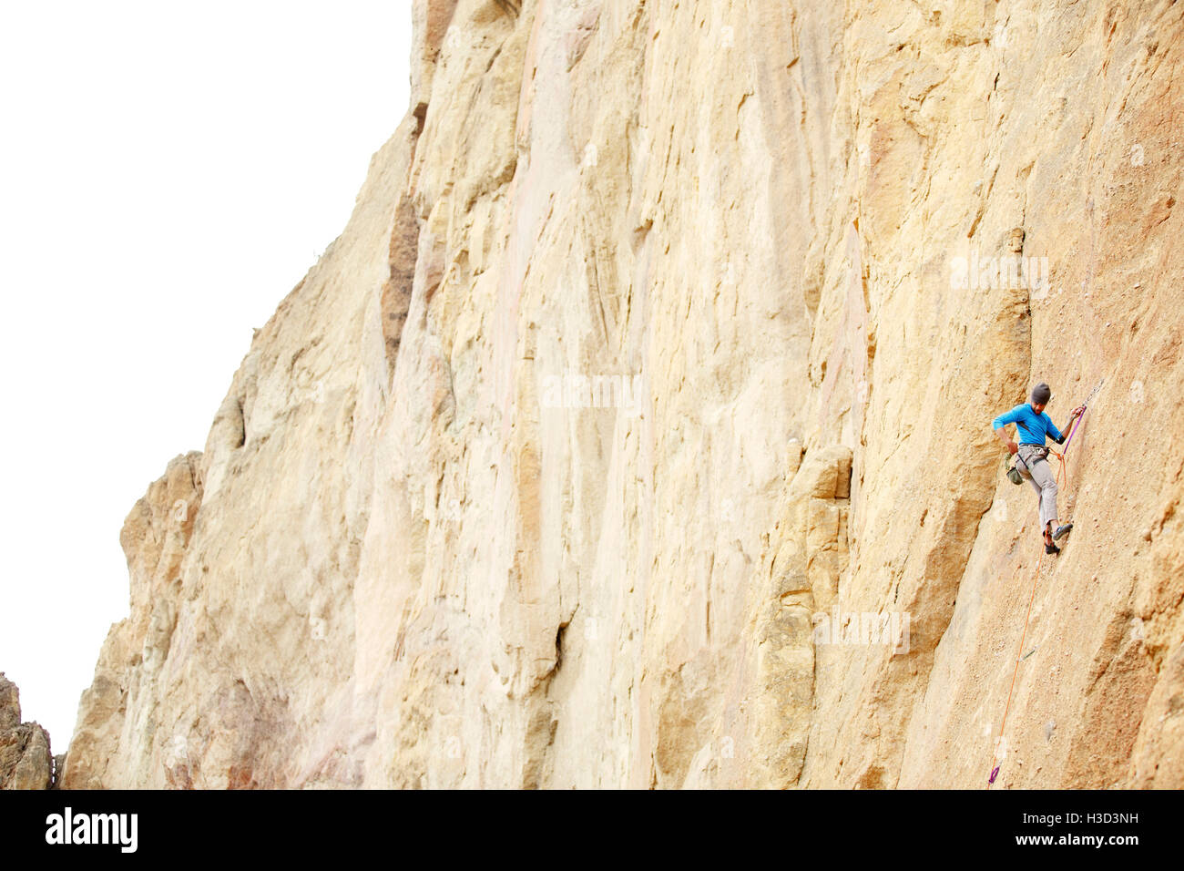 Basso angolo di visione dell'uomo rappelling giù sulla montagna Foto Stock