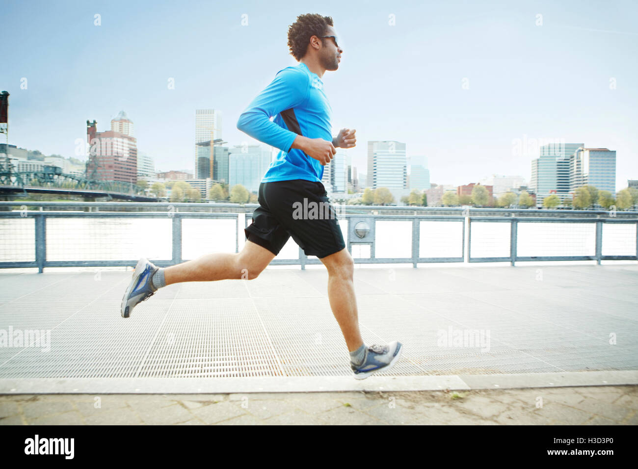 Atleta maschio jogging sul lungomare in città Foto Stock