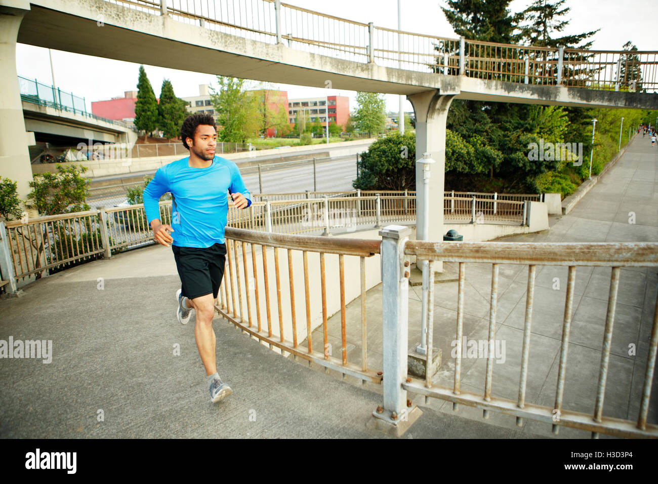 Atleta maschio jogging sul ponte Foto Stock