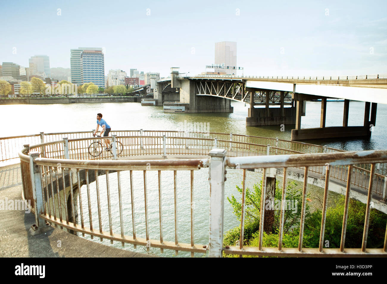 Atleta maschio equitazione Bicicletta sul ponte in città Foto Stock