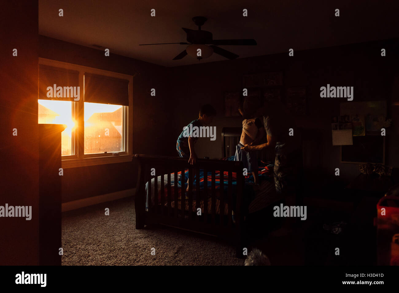 L'uomo vestire il figlio in camera da letto a casa Foto Stock