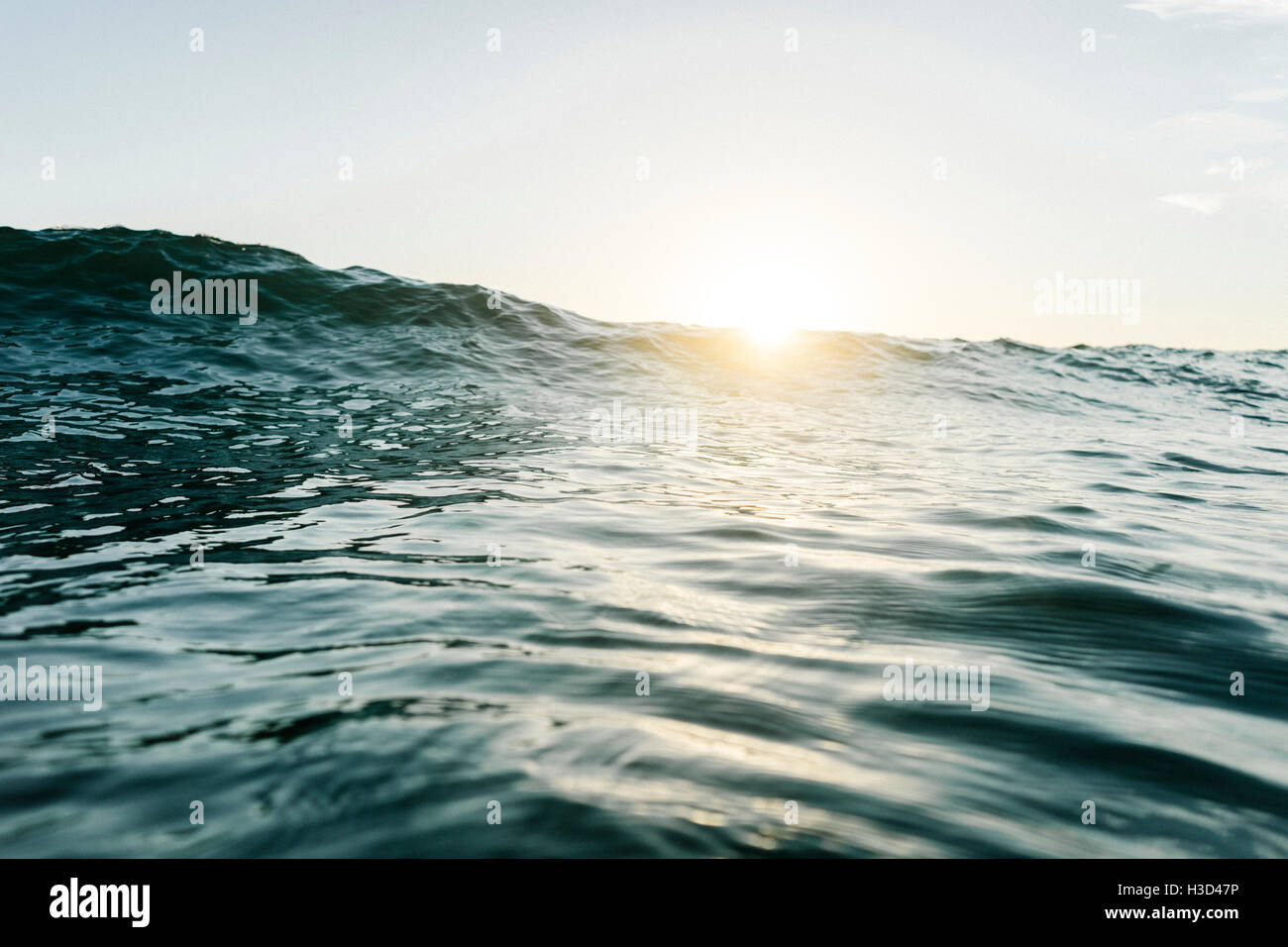 Livello di superficie delle onde che si infrangono contro il cielo chiaro durante il tramonto Foto Stock