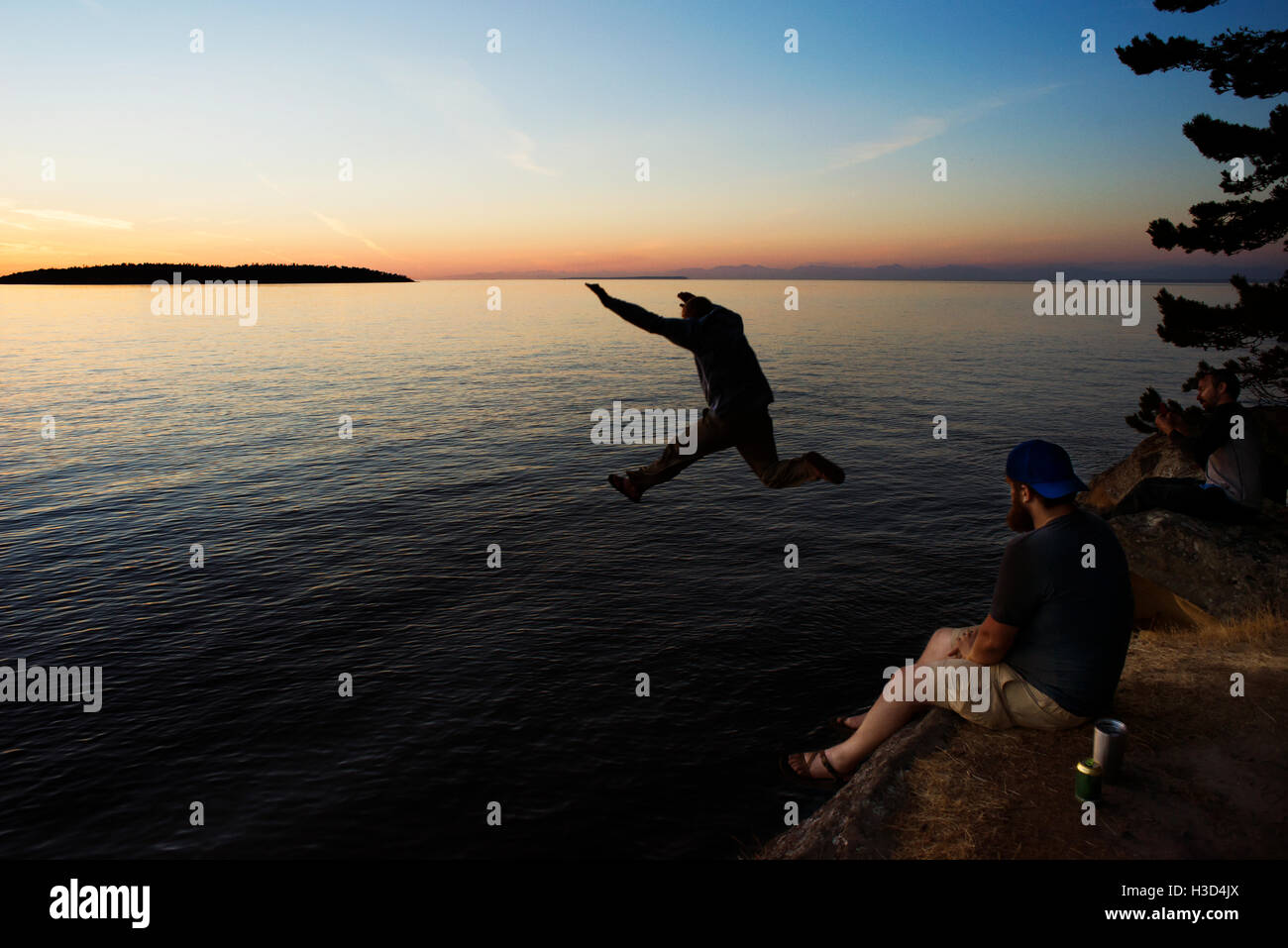 L'uomo saltando al Sucia isola contro Stretto di Georgia durante il tramonto Foto Stock