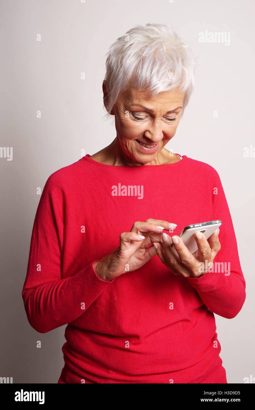 Senior donna utilizza lo smartphone Foto Stock