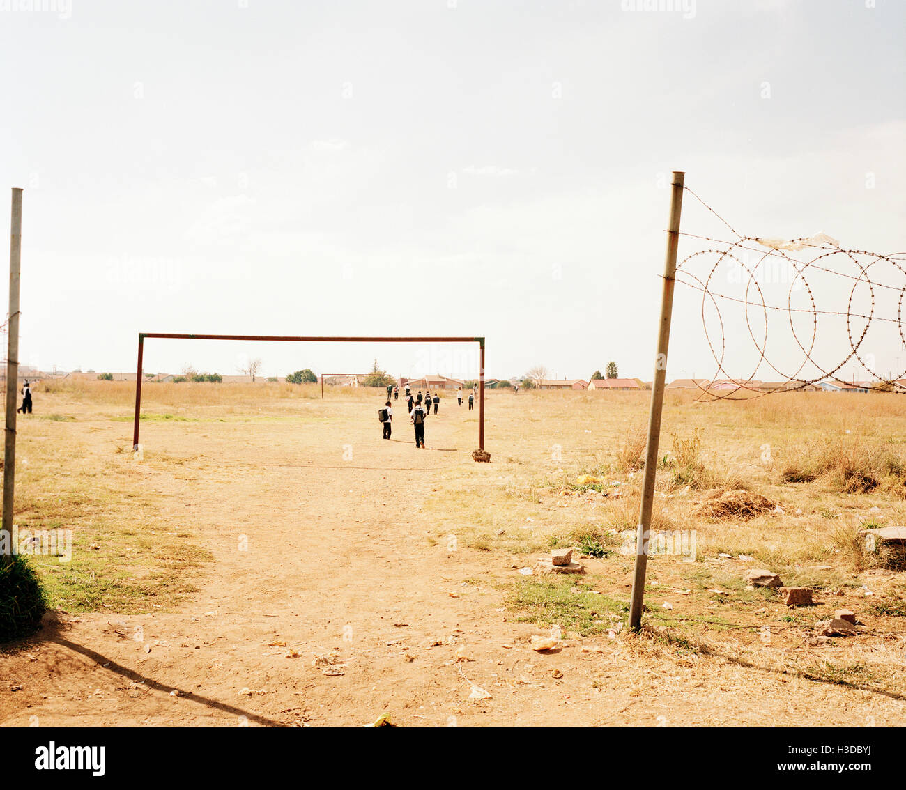 Vista attraverso un arido, comune filo spinato su un palo, gruppo di bambini a piedi di distanza. L'Africa. Foto Stock
