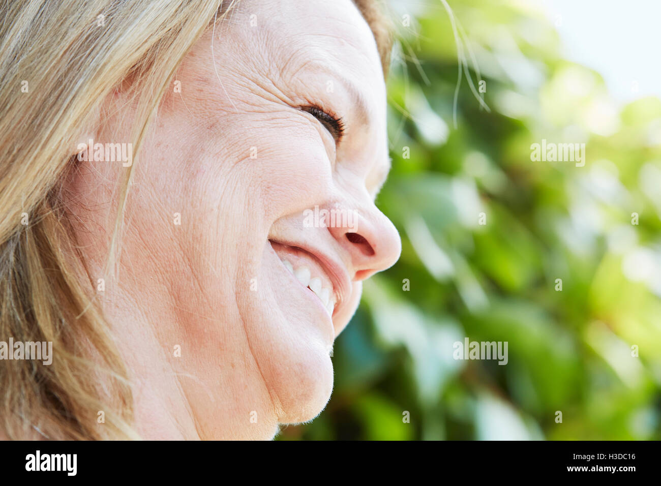 Profilo di una bionda donna matura in piedi all'esterno. Foto Stock