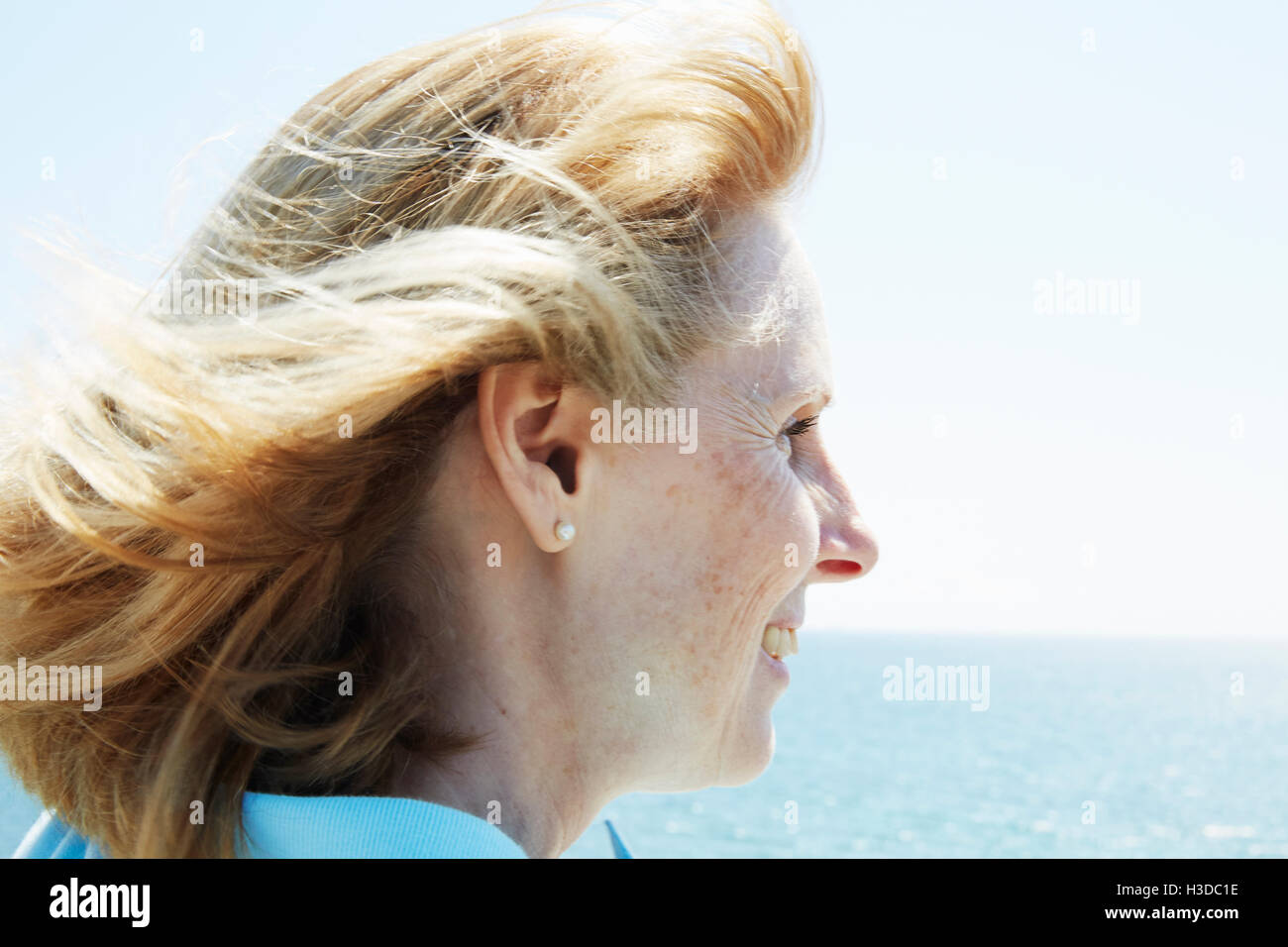 Profilo di una bionda donna matura in piedi dall'oceano. Foto Stock