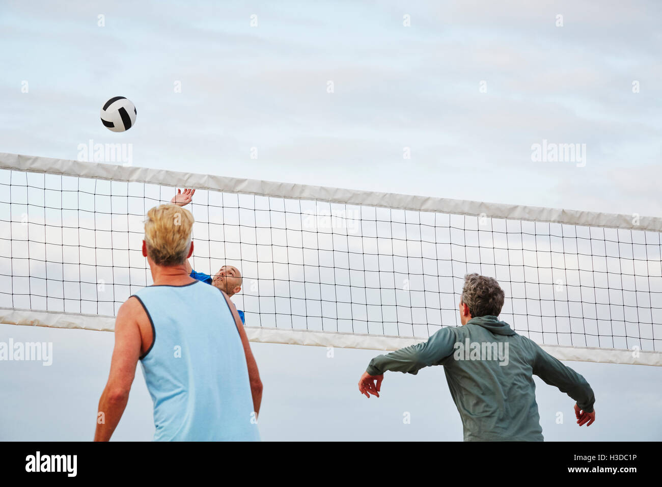Gli uomini di età matura in piedi su una spiaggia, giocando a pallavolo sulla spiaggia. Foto Stock