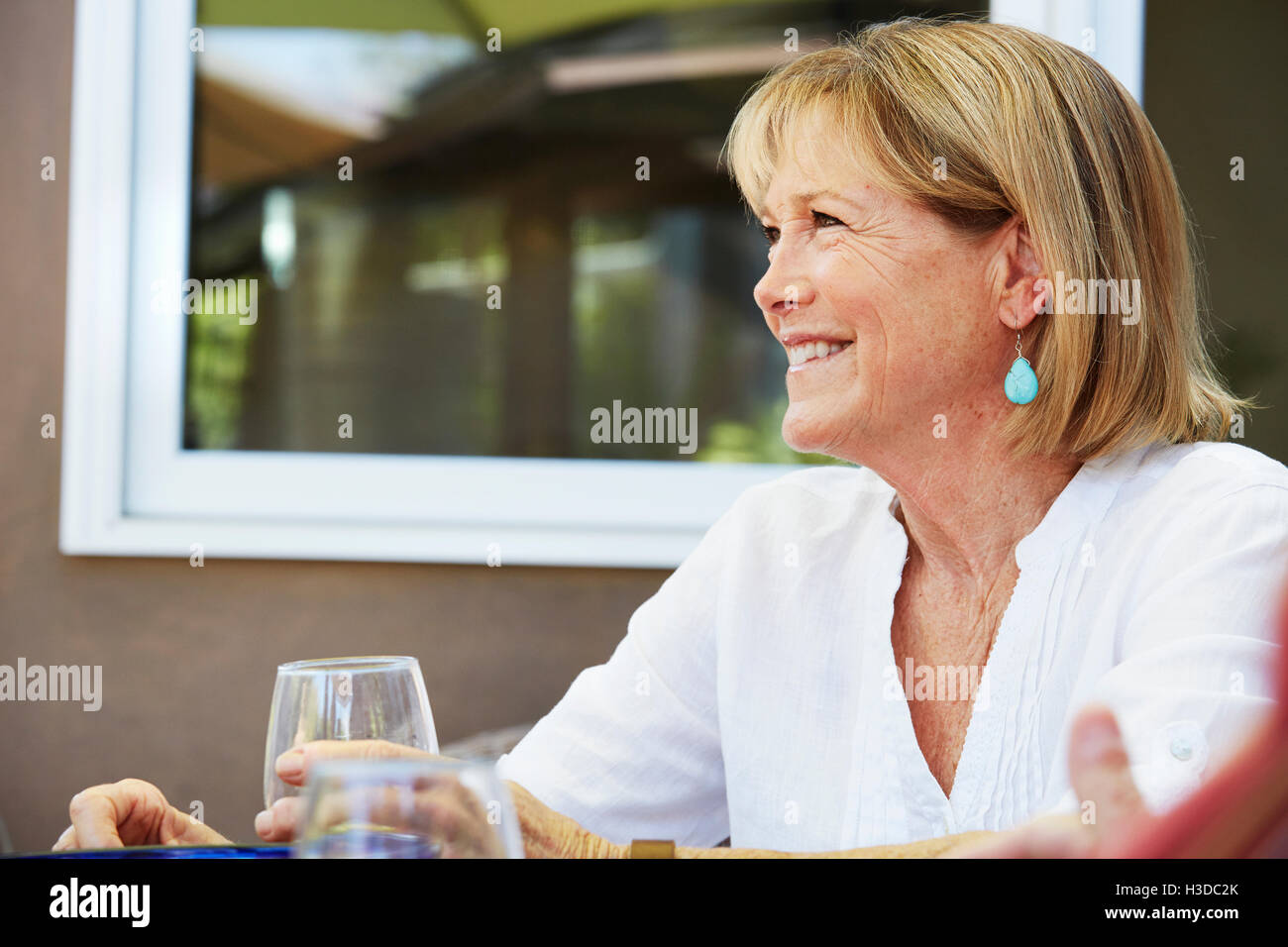 Senior sorridente donna con capelli biondi seduti all'aperto. Foto Stock
