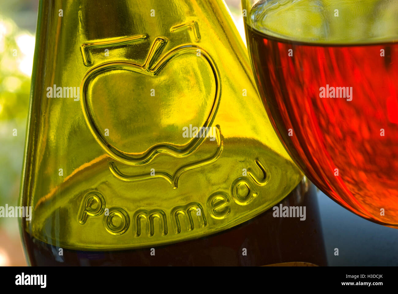 Chiudere la vista sulla bottiglia e bicchiere di alle mele de Normandie fatta con il succo di mela e Calvados in alfresco terrazza giardino situazione Foto Stock