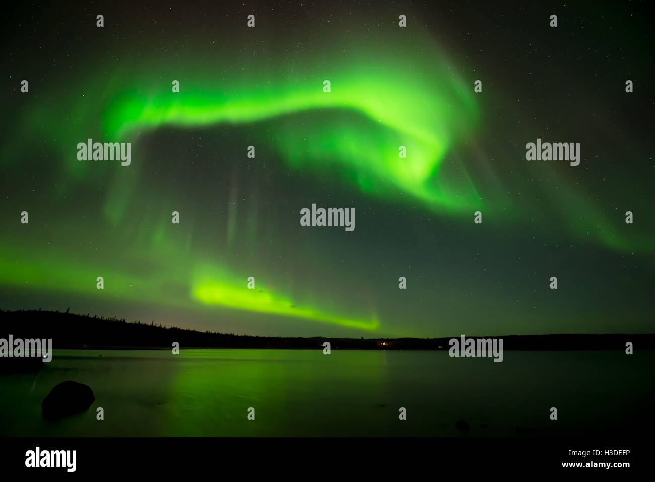Luci del nord nel cielo stellato - luminoso luci del nord il rotolamento oltre il cielo stellato su un lago. Foto Stock