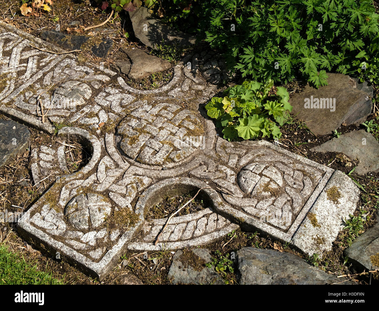 Vecchia Croce celtica disposti di piatto e sepolto per formare il giardino ornato caratteristica del percorso, Colonsay House Gardens, Isola di Colonsay, Scotland, Regno Unito Foto Stock