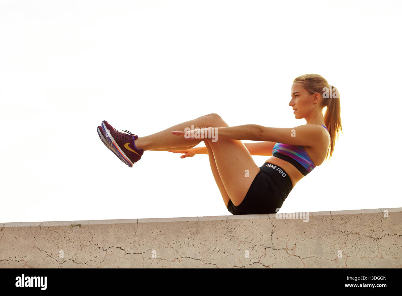 Una giovane donna atletica si allunga. Foto Stock